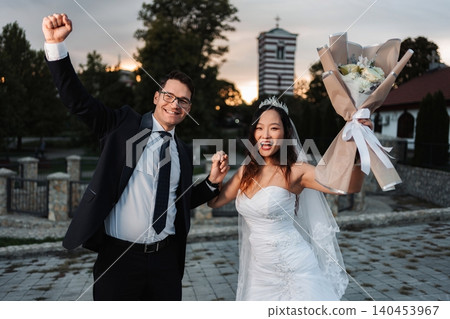 Happy newlywed couple celebrating interfaith wedding outdoors at Happy newlywed couple celebrating interfaith wedding outdoors at 140453967