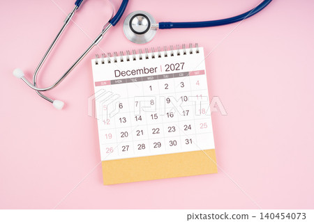 December 2027 desk calendar and Medical stethoscope on pink background. December 2027 desk calendar and Medical stethoscope on pink background. 140454073