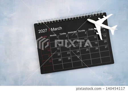 March 2027 black calendar and airplane toy on wooden table. March 2027 black calendar and airplane toy on wooden table. 140454117