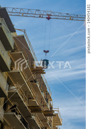 Tower Crane Lifting Concrete Bucket Between Buildings Under Construction Site Blue Sky Multi Story Development Vertical Photo Tower Crane Lifting Concrete Bucket Between Buildings Under Construction Site Blue Sky Multi Story Development Vertical Photo 140454181