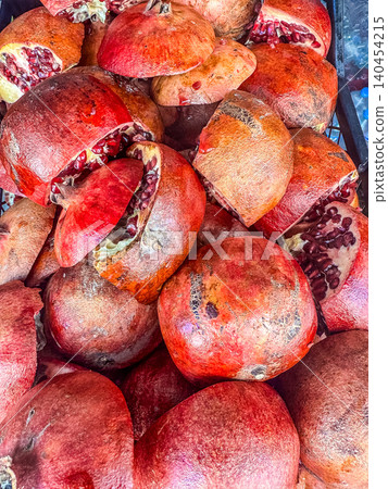 Pile of fresh ripe pomegranates cut open to reveal juicy ruby-red seeds at a farmers market. Pile of fresh ripe pomegranates cut open to reveal juicy ruby-red seeds at a farmers market. 140454215