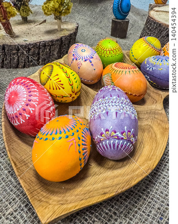 Colorful Hand-Painted Easter Eggs with Intricate Traditional Ornaments in a Wooden Plate, Rustic Spring Holiday Decoration 140454394