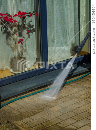 Home Exterior Maintenance: Pressure Washing Dirty Stone Pavement Tiles on an Outdoor Terrace with a High-Power Water Jet Spray Home Exterior Maintenance: Pressure Washing Dirty Stone Pavement Tiles on an Outdoor Terrace with a High-Power Water Jet Spray 140454404