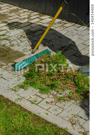 Professional Garden Maintenance: Sweeping Conifer Branch Clippings on Stone Pavement Tiles with a Turquoise Push Broom Outdoors Professional Garden Maintenance: Sweeping Conifer Branch Clippings on Stone Pavement Tiles with a Turquoise Push Broom Outdoors 140454409