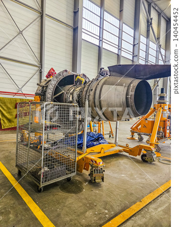 Jet engine on yellow maintenance stand inside a professional aviation hangar for repair, overhaul, and aerospace engineering. Jet engine on yellow maintenance stand inside a professional aviation hangar for repair, overhaul, and aerospace engineering. 140454452