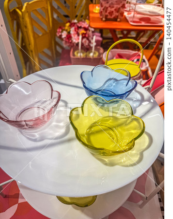 Close Up of Colorful Flower Shaped Glass Bowls in Pink Blue and Yellow on a White Tiered Serving Plate for Spring Table Setting Close Up of Colorful Flower Shaped Glass Bowls in Pink Blue and Yellow on a White Tiered Serving Plate for Spring Table Setting 140454477