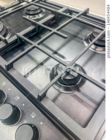Modern Black Gas Stovetop with Cast Iron Grates and Control Knobs, Close-up of Clean Kitchen Cooktop Appliance Modern Black Gas Stovetop with Cast Iron Grates and Control Knobs, Close-up of Clean Kitchen Cooktop Appliance 140454484