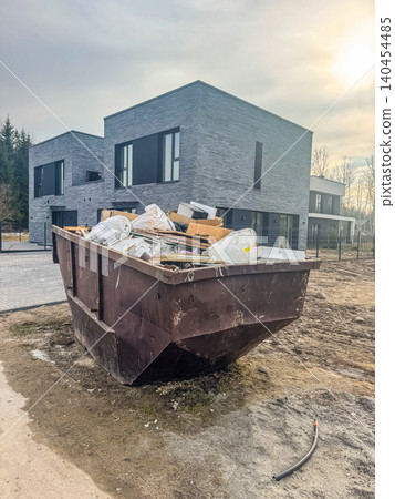 Construction Waste Skip Container in Front of Modern Residential Townhouses, Debris Management at New Home Building Site Construction Waste Skip Container in Front of Modern Residential Townhouses, Debris Management at New Home Building Site 140454485