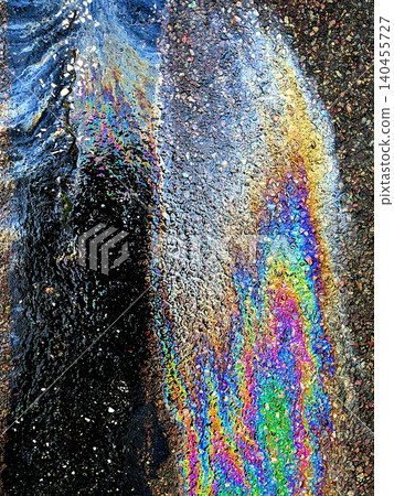 A leaked Car Oil Petrol in The Rain on a Tarmac Road Metallic Rainbow A leaked Car Oil Petrol in The Rain on a Tarmac Road Metallic Rainbow 140455727
