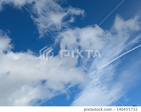 Beautiful blue summer air with fluffy white clouds and chem trail lines across the sky Beautiful blue summer air with fluffy white clouds and chem trail lines across the sky 140455732