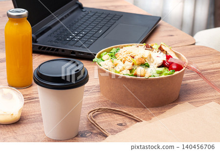 work at home on a laptop, there is food on the table, salad, coffee and juice, delivery, there are no people, work at home on a laptop, there is food on the table, salad, coffee and juice, delivery, there are no people, 140456706