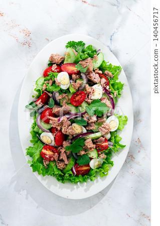 salad with canned tuna, cherry tomatoes, cucumber, and quail eggs on a white plate salad with canned tuna, cherry tomatoes, cucumber, and quail eggs on a white plate 140456717