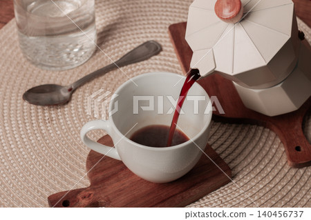 Pouring fresh coffee into a white cup from a stylish coffee maker on a wooden surface Pouring fresh coffee into a white cup from a stylish coffee maker on a wooden surface 140456737