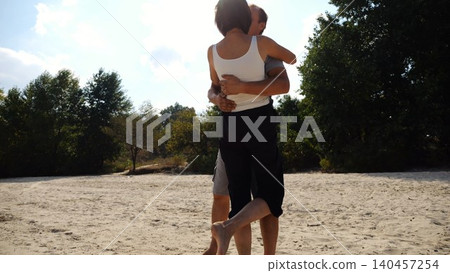 Happy couple spending time at sandy beach. Man kissing his beloved on seashore at sunny day. Carefree lovers resting during summer travel at coastline. Concept of vacation or holiday. Slow motion Happy couple spending time at sandy beach. Man kissing his beloved on seashore at sunny day. Carefree lovers resting during summer travel at coastline. Concept of vacation or holiday. Slow motion 140457254