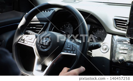 Male arms holds steering wheel while driving a motor car at city. Young man operating the automobile at urban road. Driver moving in his auto on route. Slow motion Male arms holds steering wheel while driving a motor car at city. Young man operating the automobile at urban road. Driver moving in his auto on route. Slow motion 140457258