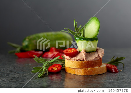Bread slices with pate, cucumber, red pepper, and rosemary. 140457578