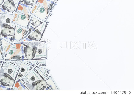 Stacked hundred-dollar bills lie scattered on a clean white surface. Each bill shows clear, crisp details and vibrant colors. The bills overlap slightly, creating a sense of abundance 140457960