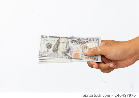 Hand holds crisp hundred-dollar bills against a clean white background. Fingers gently grip the stack, showing careful handling. No emotion visible, focus remains on the money's detail and texture Hand holds crisp hundred-dollar bills against a clean white background. Fingers gently grip the stack, showing careful handling. No emotion visible, focus remains on the money's detail and texture 140457970