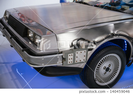 Close-up view of modified silver car resembling a time machine. Features stainless steel body, unique wheel design, and blue LED lights illuminating the reflective floor. 140459046