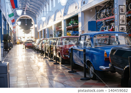 Row of colorful vintage cars displayed inside a bright classic automobile museum with retro architecture and warm sunlight. Historic transportation vehicles and collectible retro automobiles create a Row of colorful vintage cars displayed inside a bright classic automobile museum with retro architecture and warm sunlight. Historic transportation vehicles and collectible retro automobiles create a 140459082