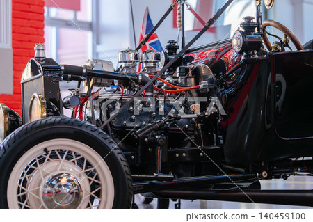 Closeup photo of a vintage hot rod engine with exposed mechanical parts, chrome components, and retro automotive design. Historic custom automobile displayed inside a classic transportation museum Closeup photo of a vintage hot rod engine with exposed mechanical parts, chrome components, and retro automotive design. Historic custom automobile displayed inside a classic transportation museum 140459100