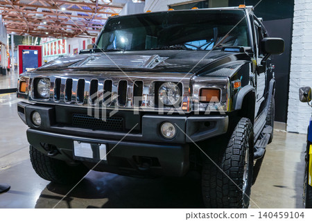 Black luxury SUV with chrome grille and rugged tires displayed inside a modern automotive museum. Premium off road vehicle showcases powerful transportation design and luxury automotive engineering. 140459104