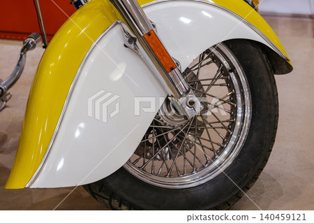 Close-up detail of motorcycle front wheel and fender showcasing chrome accents and two-tone design. The polished surfaces reflect light, highlighting the craftsmanship of custom motorcycle design. 140459121