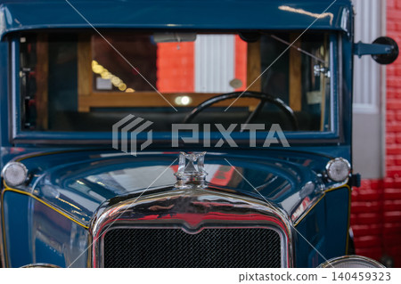 Vintage blue truck showcases polished grill and hood ornament in indoor garage setting. Architectural details and brick wall enhance nostalgic atmosphere during daytime. Vintage blue truck showcases polished grill and hood ornament in indoor garage setting. Architectural details and brick wall enhance nostalgic atmosphere during daytime. 140459323