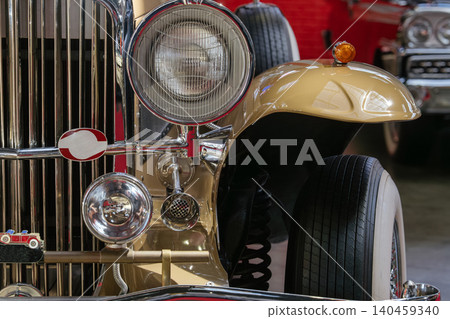 Vintage car showcases elegant front grille and chrome accents in exhibition hall. Nostalgic atmosphere enhanced by bright indoor lighting and classic design elements. Vintage car showcases elegant front grille and chrome accents in exhibition hall. Nostalgic atmosphere enhanced by bright indoor lighting and classic design elements. 140459340