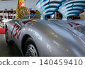 Vintage silver racing car with red numbers and blue wings in exhibition hall 140459410