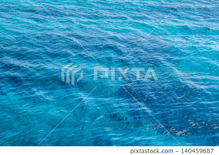 Gentle waves ripple across deep turquoise water under bright sunlight, creating a tranquil coastal environment perfect for relaxation. Gentle waves ripple across deep turquoise water under bright sunlight, creating a tranquil coastal environment perfect for relaxation. 140459687