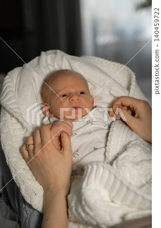 Warm light filters through the window as a mother cradles her newborn baby, wrapped in a soft white blanket, showcasing a moment of love and tenderness. Warm light filters through the window as a mother cradles her newborn baby, wrapped in a soft white blanket, showcasing a moment of love and tenderness. 140459722