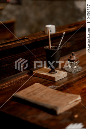 A rustic desk displays a vintage ink pot, brushes, and a worn book, capturing a nostalgic atmosphere and a sense of creativity and history. A rustic desk displays a vintage ink pot, brushes, and a worn book, capturing a nostalgic atmosphere and a sense of creativity and history. 140459727