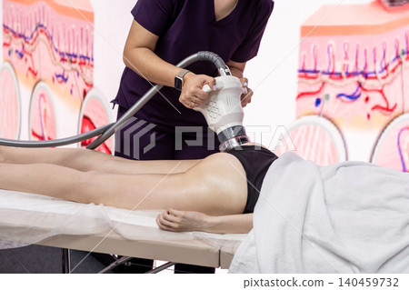 A professional uses advanced equipment for body contouring on a clients thigh in a modern clinic, showcasing the latest aesthetic techniques. A professional uses advanced equipment for body contouring on a clients thigh in a modern clinic, showcasing the latest aesthetic techniques. 140459732