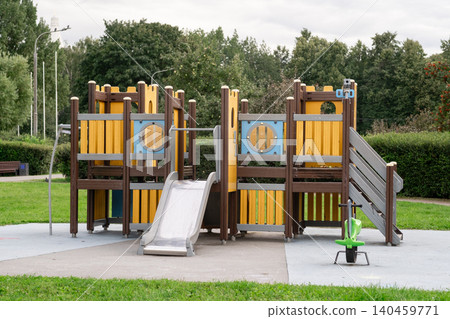 Children enjoy outdoor playtime at a vibrant playground filled with slides and climbing frames surrounded by greenery on a cloudy day Children enjoy outdoor playtime at a vibrant playground filled with slides and climbing frames surrounded by greenery on a cloudy day 140459771