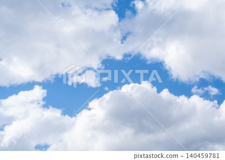 The sky showcases a vibrant blue backdrop filled with soft, fluffy white clouds drifting peacefully above, creating a tranquil atmosphere. 140459781