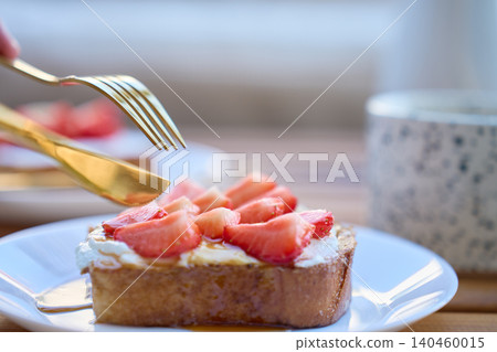 French toast with strawberries and honey served on plate with fork and knife French toast with strawberries and honey served on plate with fork and knife 140460015