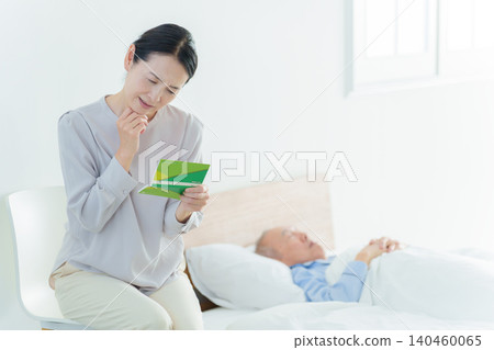 一位神情憂慮的女士看著她的銀行存摺;由於承擔了照顧家人的責任,她已經破產了。 一位神情憂慮的女士看著她的銀行存摺;由於承擔了照顧家人的責任,她已經破產了。 140460065