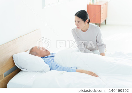 A woman caring for a bedridden elderly person A woman caring for a bedridden elderly person 140460302
