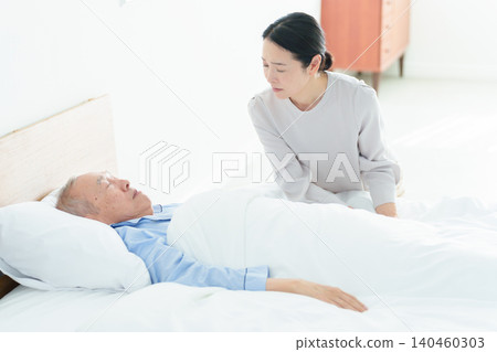 A woman caring for a bedridden elderly person A woman caring for a bedridden elderly person 140460303