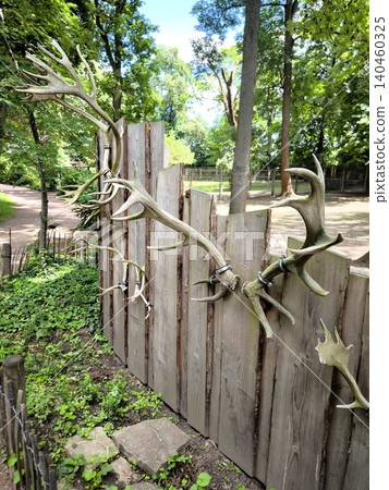 A decorative wooden fence adorned with deer antlers in a park. A decorative wooden fence adorned with deer antlers in a park. 140460325