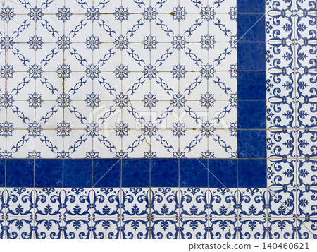 Classic Portuguese azulejos wall with a geometric arrangement of intricate white and blue floral patterned ceramic tiles separated by a deep blue border 140460621