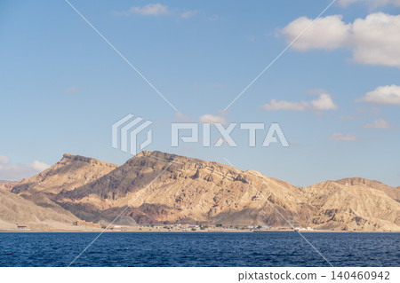 Coastal mountains rise dramatically above tranquil waters under a bright sky, highlighting the beauty of remote natural landscapes. Coastal mountains rise dramatically above tranquil waters under a bright sky, highlighting the beauty of remote natural landscapes. 140460942