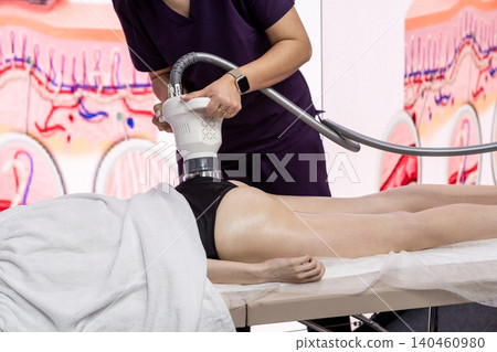 A spa professional performs a body contouring treatment on a clients thigh using advanced technology, highlighting wellness trends in aesthetic procedures. A spa professional performs a body contouring treatment on a clients thigh using advanced technology, highlighting wellness trends in aesthetic procedures. 140460980