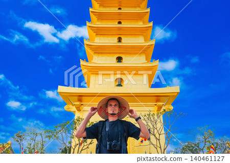 happy tourist male at golden tower on Vietnamese Buddhist pagoda Truc Lam Phung Thuy Son in Nha Trang in Vietnam. Travel, tourism and sightseeing in Asia happy tourist male at golden tower on Vietnamese Buddhist pagoda Truc Lam Phung Thuy Son in Nha Trang in Vietnam. Travel, tourism and sightseeing in Asia 140461127