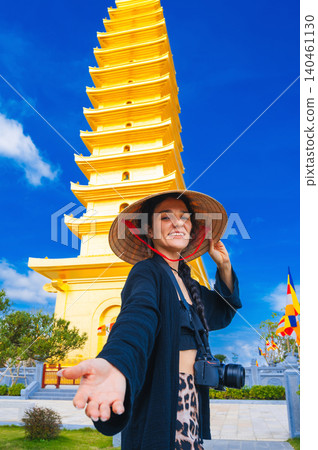 happy tourist woman at the golden tower on the Vietnamese Buddhist pagoda Truc Lam Phung Thuy Son in Nha Trang in Vietnam. Travel, tourism and sightseeing in Asia 140461130