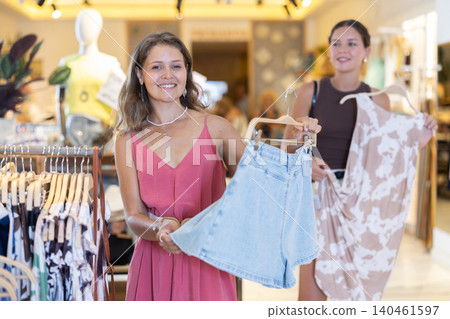 Two young women choosing shorts and dress in store Two young women choosing shorts and dress in store 140461597
