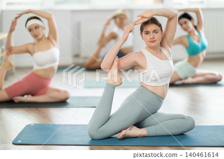 Group of girls doing Pilates or yoga - stretching the body in various poses Group of girls doing Pilates or yoga - stretching the body in various poses 140461614
