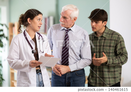 Senior man patient and son discuss reading test results with guy doctor Senior man patient and son discuss reading test results with guy doctor 140461615