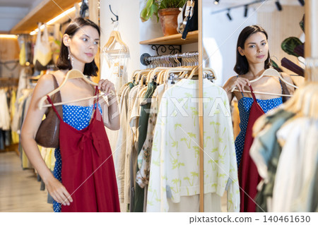 Adult woman chooses dress in clothing store 140461630